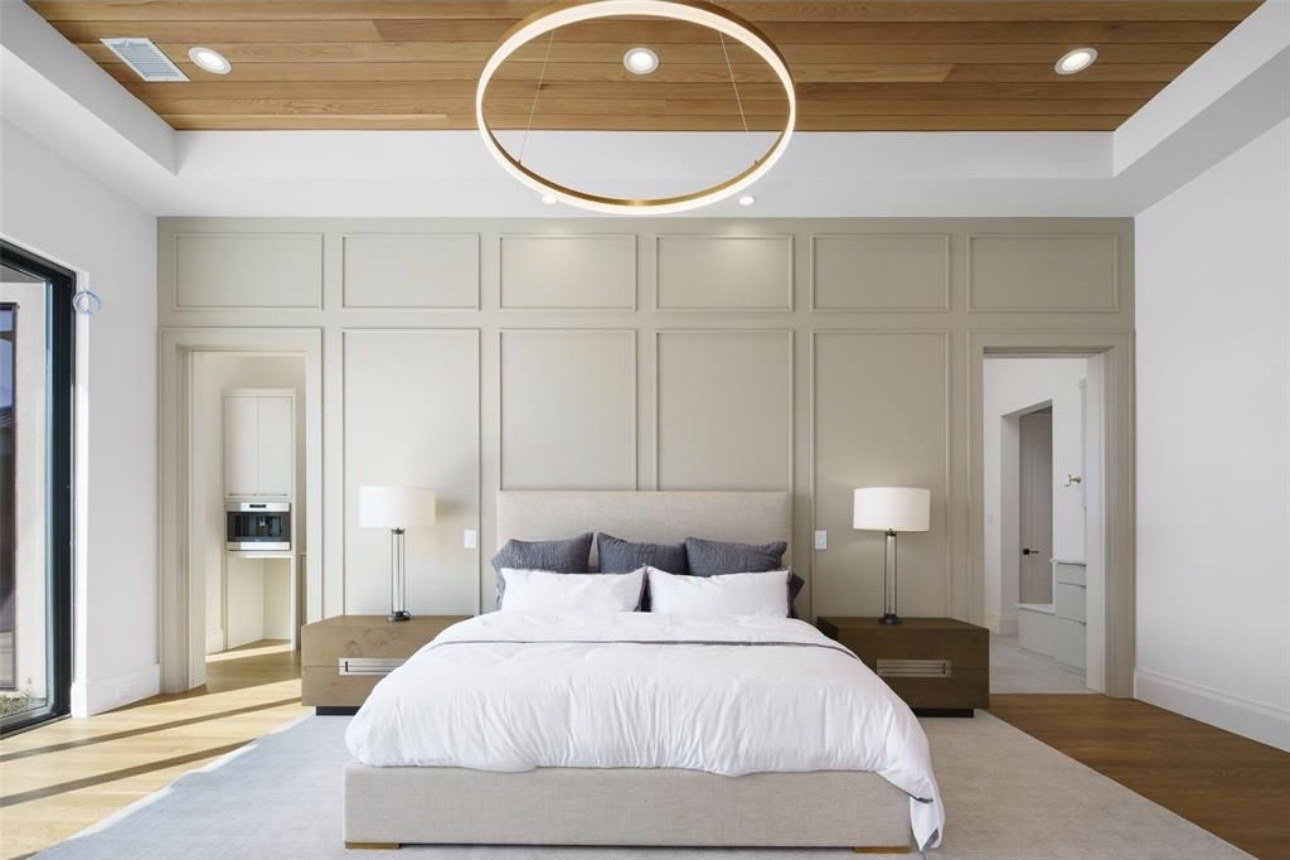 Primary suite with paneled wall and wood ceiling