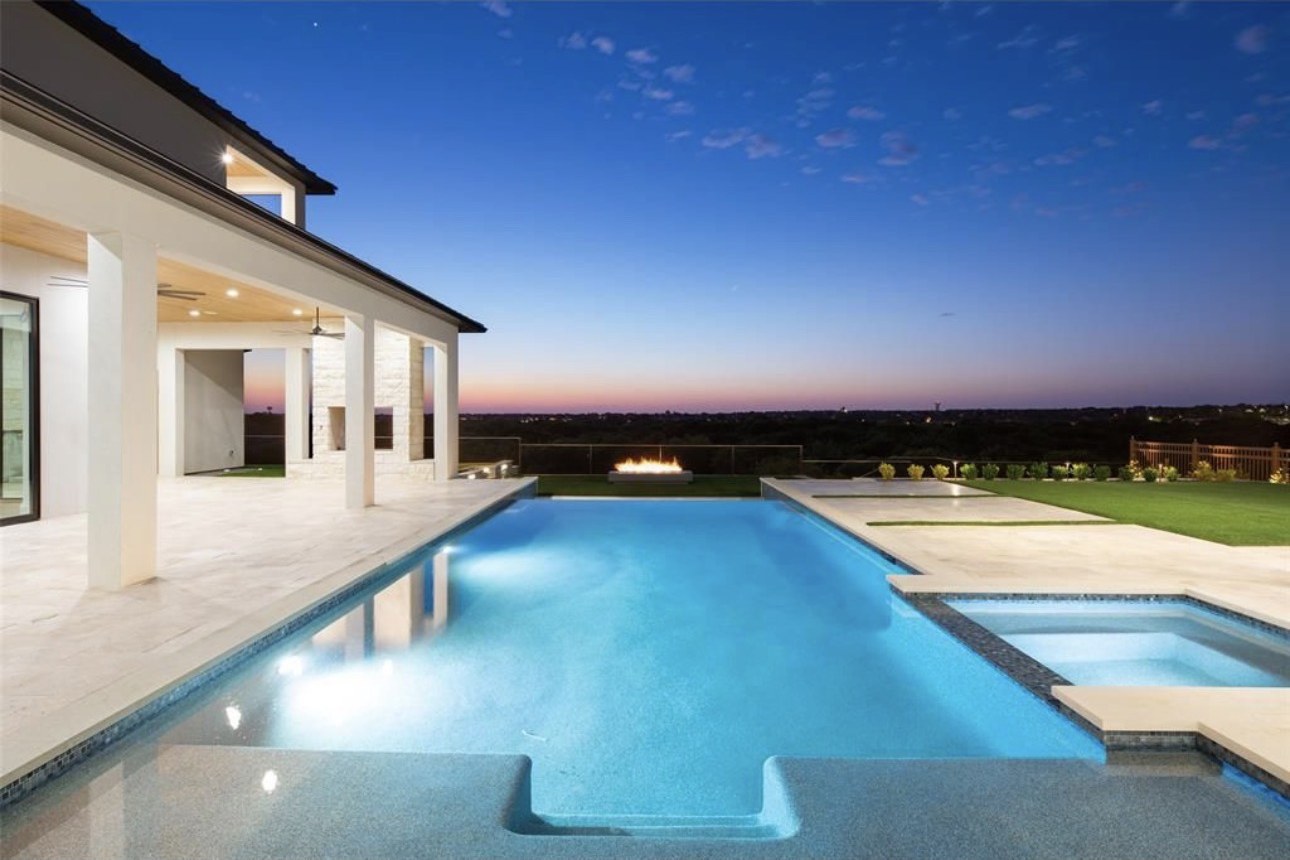 Resort-style pool and spa overlooking the tree line at dusk